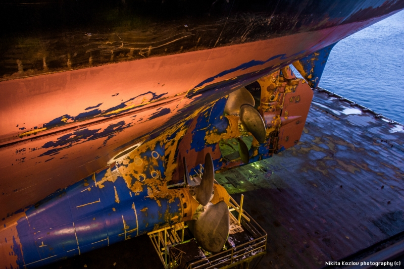 The vessel is elevated due to its body maintenance. The workers are checking and fixing its rudder s...